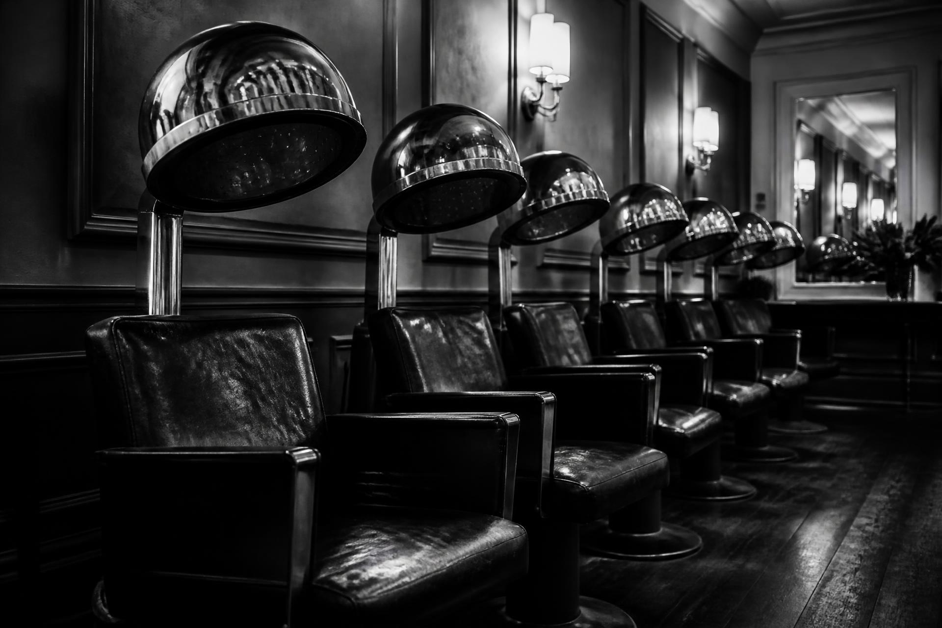 Row of vintage salon chairs with chrome hood dryers at Sur Mesure Salon